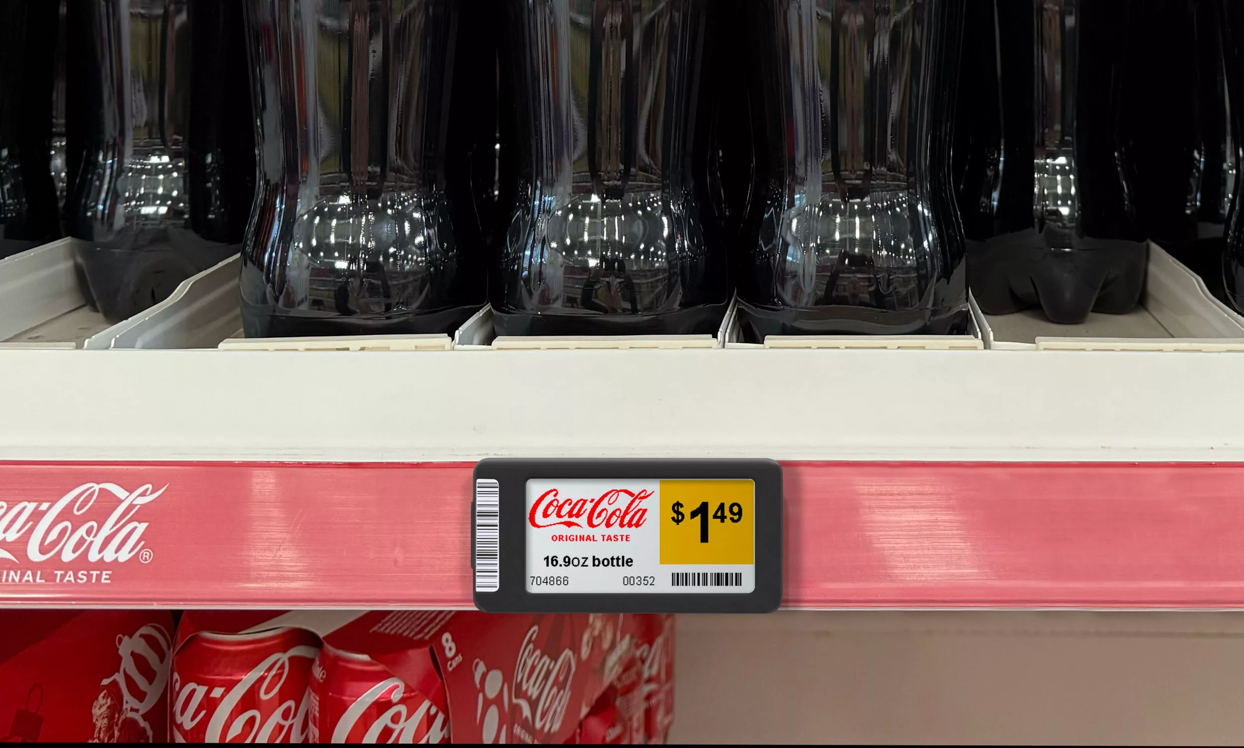 Coca Cola bottles in a store with a Displaydata ESL showing pricing and product info